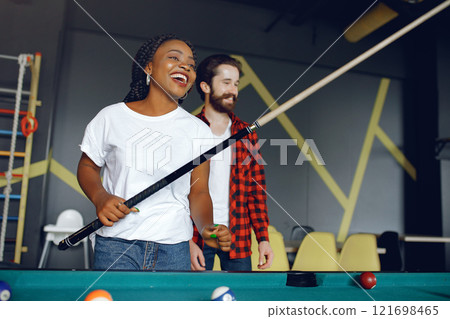 Black girl in a white t-shirt. Couple playing a billiard 121698465