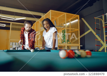 Black girl in a white t-shirt. Couple playing a billiard Black girl in a white t-shirt. Couple playing a billiard 121698470