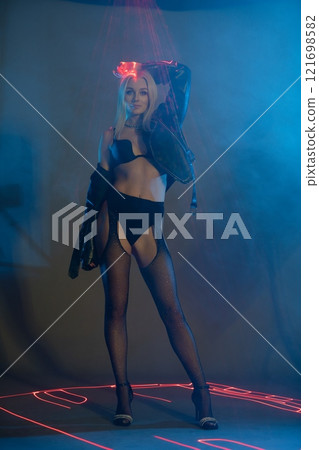 Stylish model posing in a futuristic setting with neon lights at night 121698582
