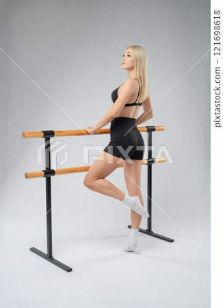 Young woman practicing ballet at a dance studio with a ballet barre Young woman practicing ballet at a dance studio with a ballet barre 121698618