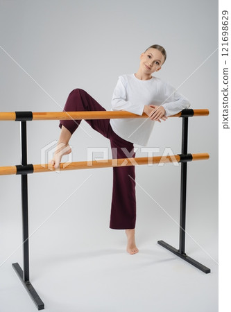 Graceful girl practicing dance at the barre, showcasing her athleticism and art Graceful girl practicing dance at the barre, showcasing her athleticism and art 121698629