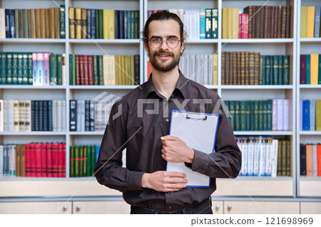 Portrait young male with clipboard in library Portrait young male with clipboard in library 121698969