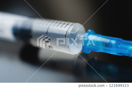 Syringe filled with liquid positioned on a dark surface in a healthcare setting 121699323