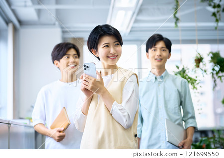 一位穿著便衣的年輕女商人在辦公室裡操作智能手機 一位穿著便衣的年輕女商人在辦公室裡操作智能手機 121699550