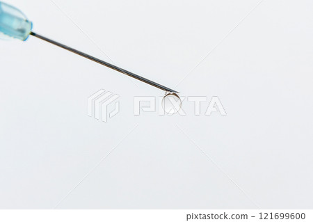 At the tip of the medical needle is a transparent drop 121699600