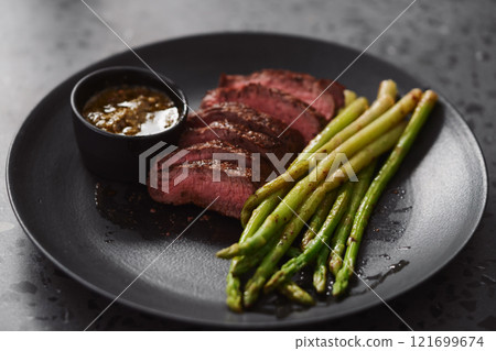 New york steak with asparagus on black plate with pesto sauce New york steak with asparagus on black plate with pesto sauce 121699674