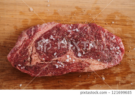 Raw ribeye steak spiced and ready to cook on oak board 121699685