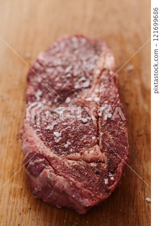 Raw ribeye steak spiced and ready to cook on oak board 121699686