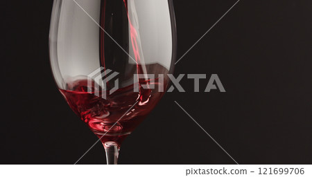 pour red wine into wineglass over black baground pour red wine into wineglass over black baground 121699706