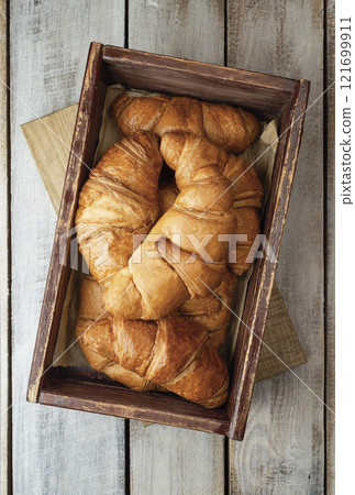 Coffee with croissants. Baked crispy croissant on a wooden board, breakfast. Homemade Croissant . 121699911