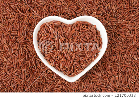red rice in a ceramic bowl as a background. Top view. Flat lay 121700338