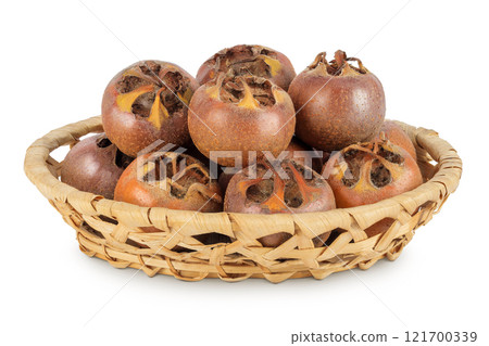 Brown fresh medlars in a wicker basket isolated on white background. Mespilus germanica close-up 121700339