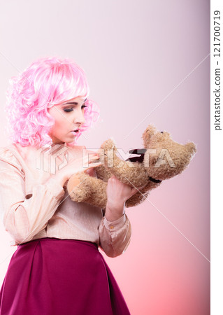 childlike woman with teddy bear toy 121700719