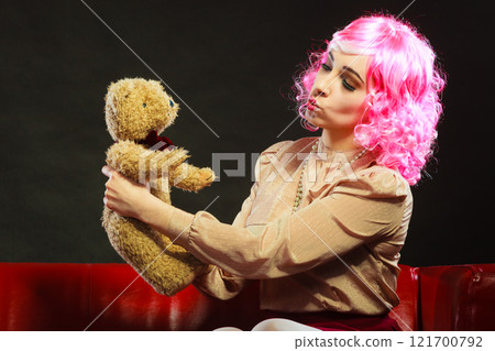 childlike woman and teddy bear sitting on couch 121700792