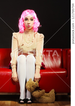 childlike woman and teddy bear sitting on couch 121700794