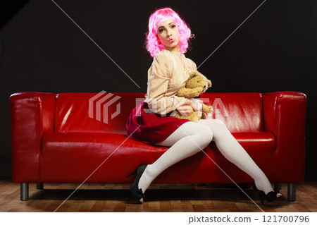 childlike woman and teddy bear sitting on couch childlike woman and teddy bear sitting on couch 121700796