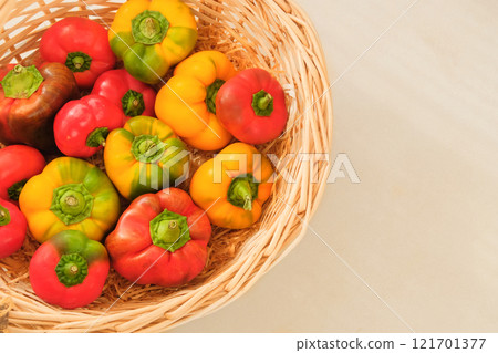 Sweet peppers in a straw basket. Orange and red ripe vegetables. Top view. Place for text. Sweet peppers in a straw basket. Orange and red ripe vegetables. Top view. Place for text. 121701377