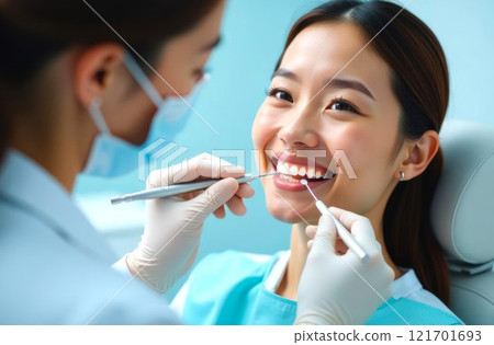 A dentist examining a patient's teeth, young asian female at the dentist's. Face of a asian woman and hands of a dentist. Doctor emphasizing dental health and hygiene 121701693