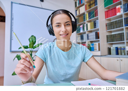Webcam view of teenage girl, high school student, in headphones, talking to camera 121701882