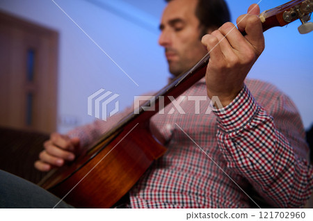 Man Playing Acoustic Guitar in a Cozy Indoor Setting 121702960