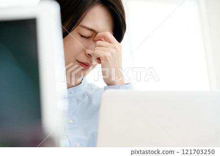 Woman whose eyes are tired from computer work Woman whose eyes are tired from computer work 121703250