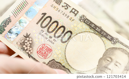 A man is holding a 10,000 yen bill 121703414