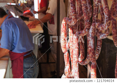 Front of a butcher shop with sausages hanging from the ceiling Front of a butcher shop with sausages hanging from the ceiling 121704014