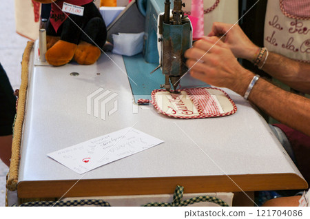 A person's hand painting letters onto a sewing machine 121704086