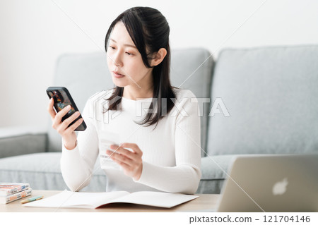 A middle-aged woman keeping a household account book on her smartphone A middle-aged woman keeping a household account book on her smartphone 121704146