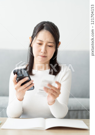A middle-aged woman with a receipt in hand, struggling with cutting expenses 121704153
