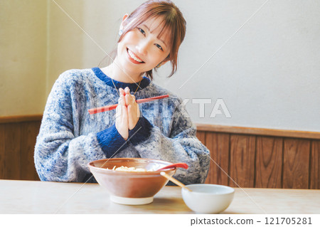 Young woman eating ramen after saying itadakimasu 121705281
