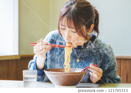 Happy young woman eating delicious ramen 121705313