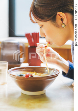 Happy young woman eating delicious ramen 121705317