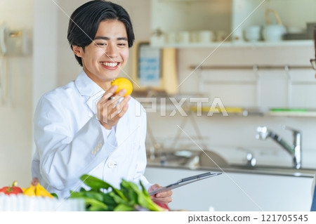 A young male registered dietitian in a white coat recommending vegetables and fruits 121705545