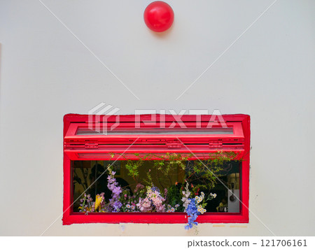 White wall with decorative red window and beautiful flowers and red ballons White wall with decorative red window and beautiful flowers and red ballons 121706161