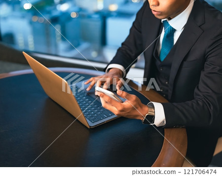 A businessman working with a laptop and smartphone in a high-rise office A businessman working with a laptop and smartphone in a high-rise office 121706474