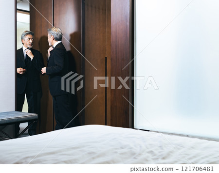 Middle-aged man looking in the mirror and grooming himself 121706481