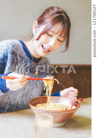 Happy young woman eating delicious ramen 121706527