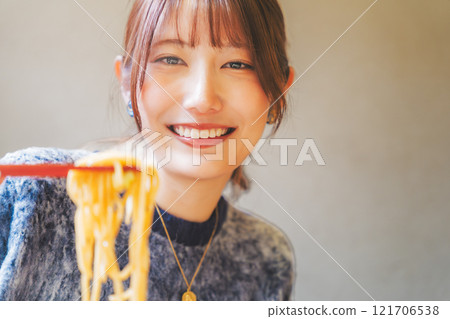 Happy young woman eating delicious ramen 121706538