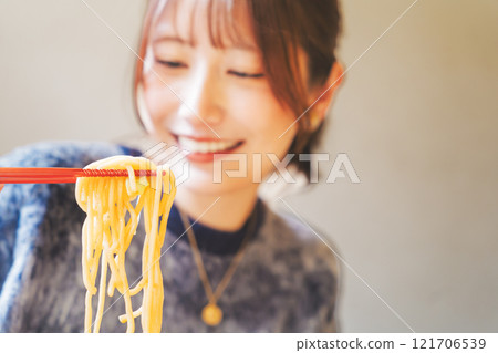 Happy young woman eating delicious ramen 121706539