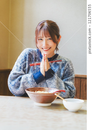 Young woman eating ramen after saying itadakimasu 121706555