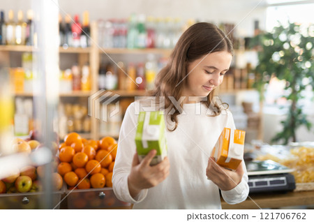 Teenage girl choosing peach and apple juices Teenage girl choosing peach and apple juices 121706762