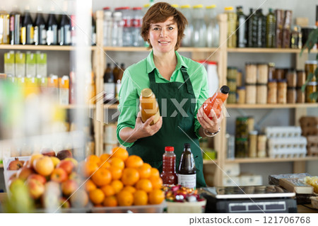 Woman seller stands in trading hall of store with goods in hand 121706768