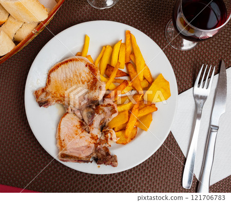 Juicy roasted loin chops served with french fries closeup 121706783
