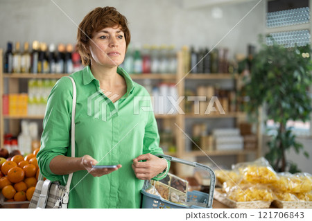 Woman with phone in hands walks around store 121706843