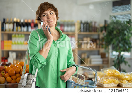 Woman with phone in hands walks around store 121706852