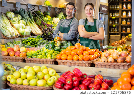 Male and woman sellers offering fruit and vegetables standing near stalls in fruit market 121706876