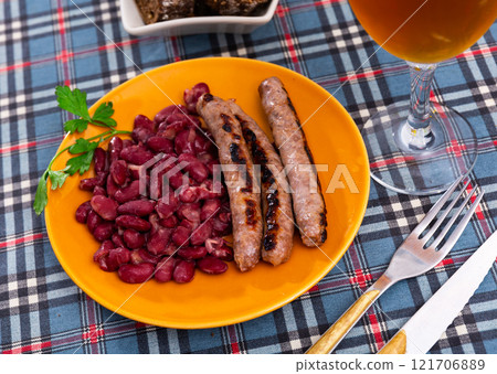 Fried red beans and sausage served on plate and decorated with greenery, traditional dish of Catalonia 121706889