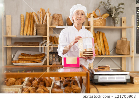 Elderly woman seller weighs piece of cake 121706908