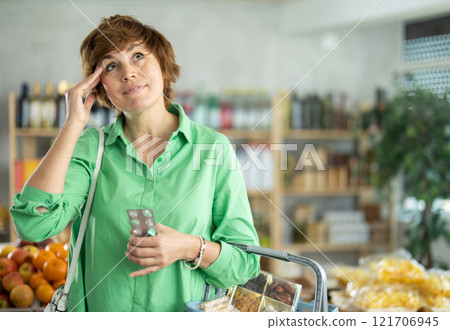 Adult woman with headache pills in grocery store 121706945